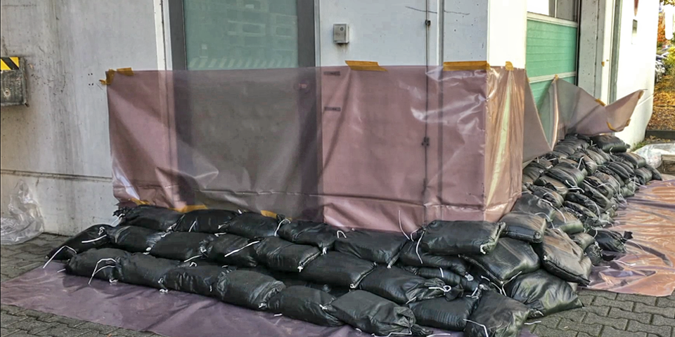 Sandsäcke und Plastikfolien verhindern, dass Wasser in die Gebäude fließt